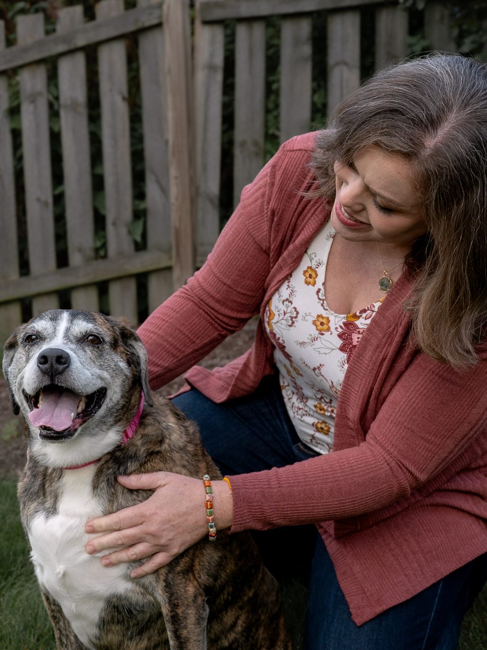 Dr. Christie kneeling beside a happy senior dog